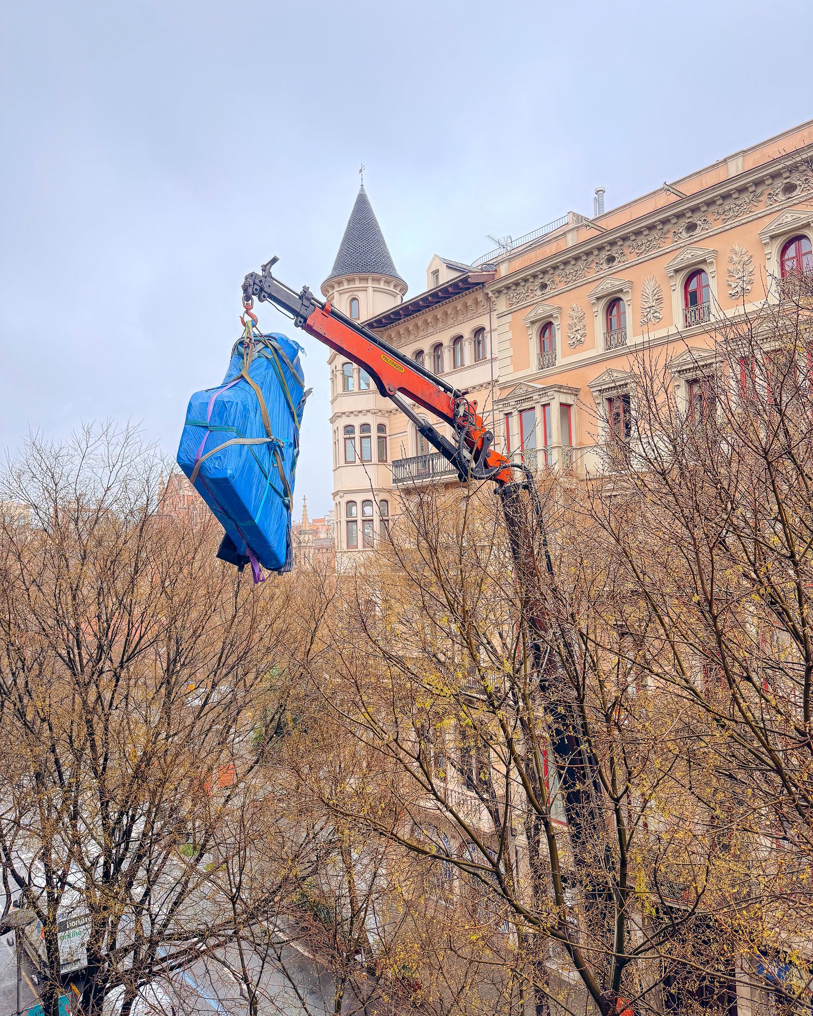 Grúa articulada elevando piano en Barcelona — servicio de traslado especial